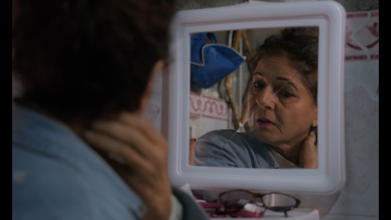 Fatna El Bouih examines herself in a mirror